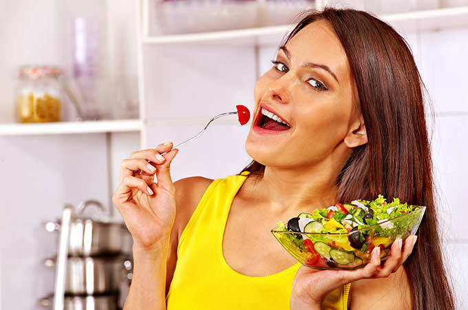 bigstock-Happy-woman-eating-salad-at-ki-70423444