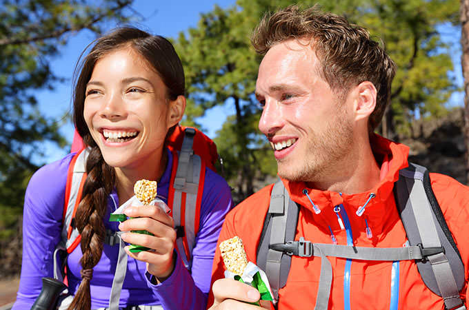 bigstock-Couple-eating-muesli-bar-hikin-74257219