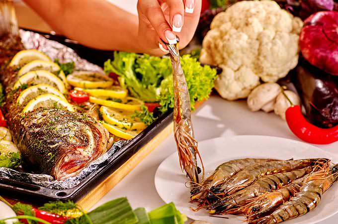 bigstock-Happy-woman-prepare-fish-at-ov-92116349