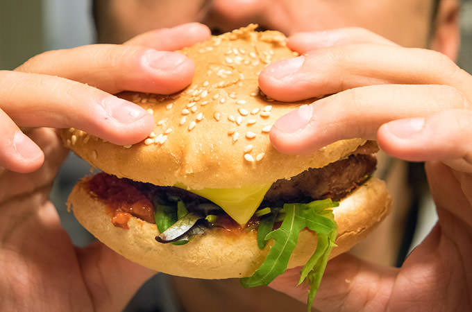 bigstock-Man-eating-an-hamburger-in-a-f-102973139